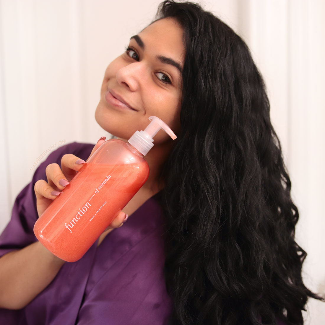 Miranda looking to camera holding up the Function of Beauty Shampoo with her curly hair falling over her shoulder | Function of Beauty Customized Hair Care Review: Is it worth i? | Slashed Beauty