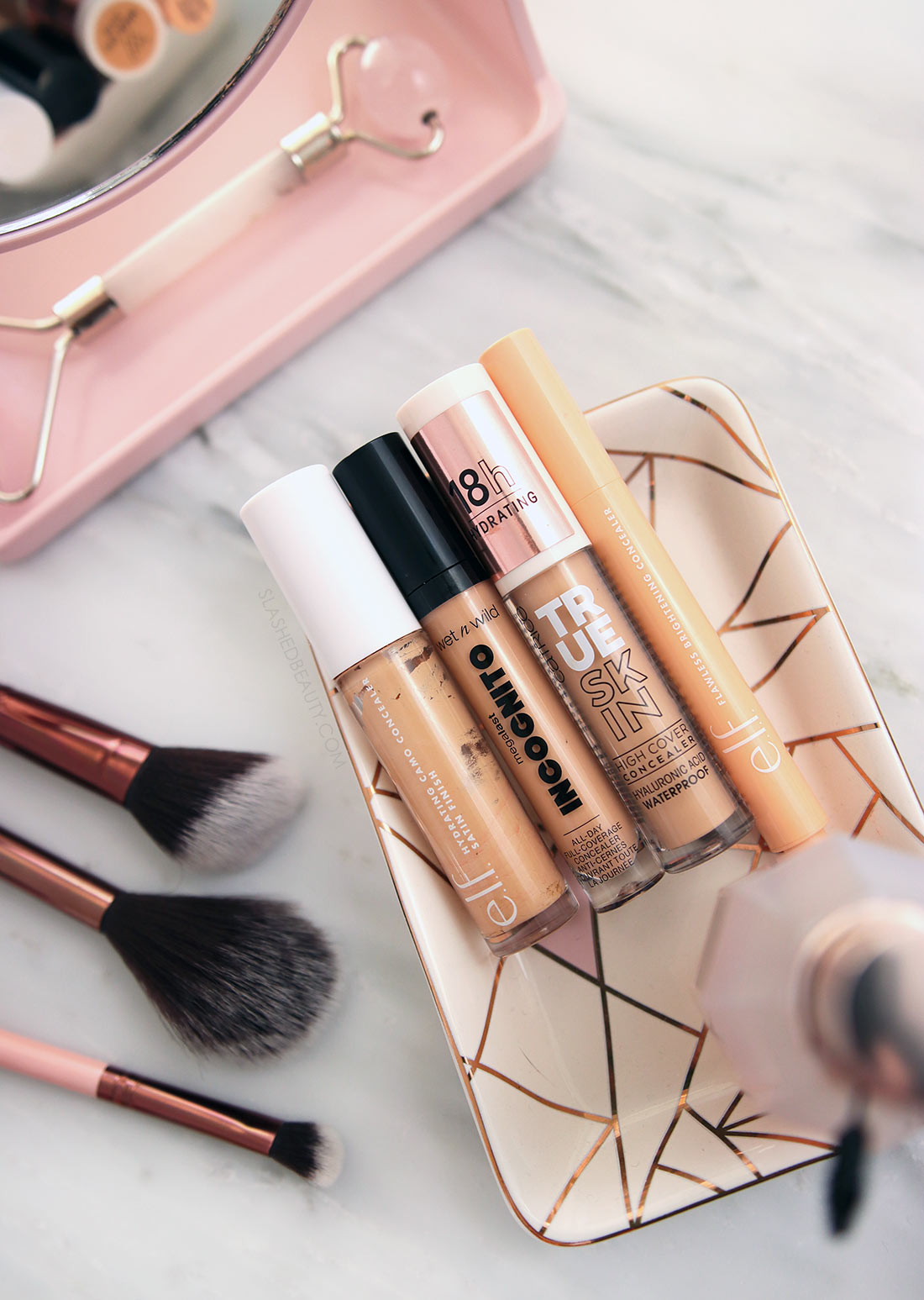 Four drugstore concealers lying on a tray on a marble surface. | The Best Drugstore Concealers Under $10 in 2022 | Slashed Beauty
