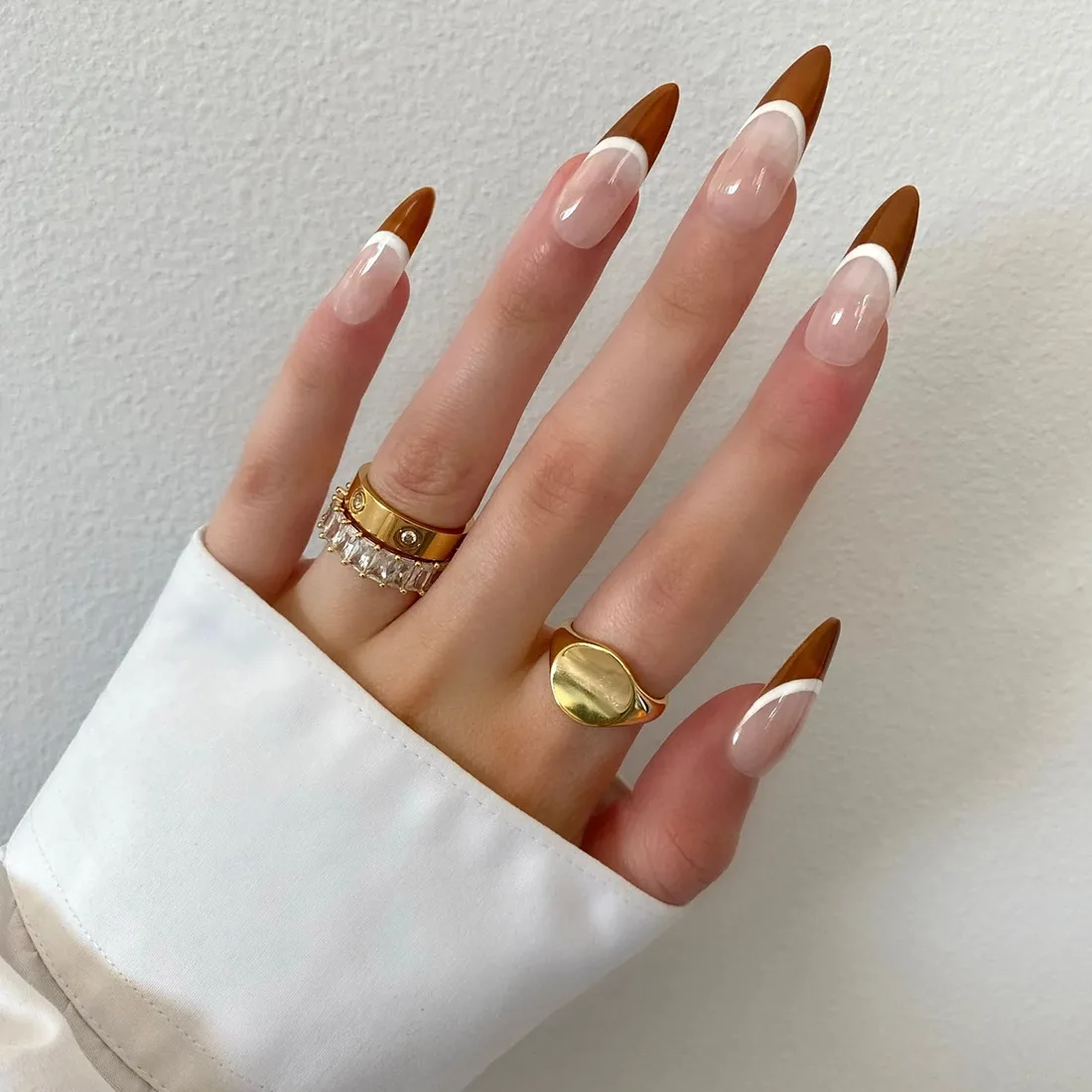 Close up of hand wearing stilleto nail press ons with a brown and white french tip design for fall | Trendy Fall Nail Designs You Can Buy as Press-Ons on Etsy | Slashed Beauty