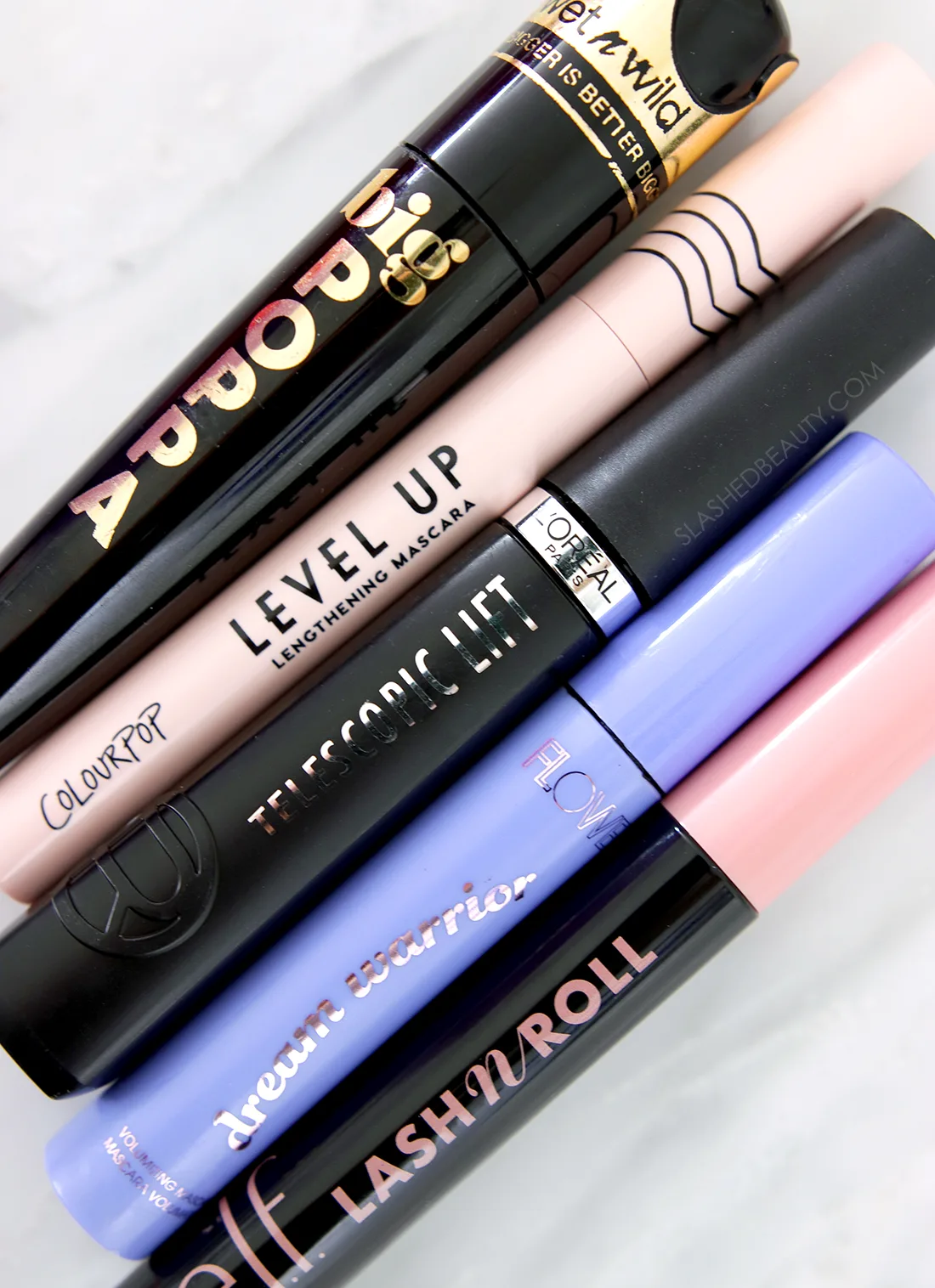 Drugstore mascaras lying flat on a marble surface | 5 Best Drugstore Mascaras for Short Lashes in 2023 | Slashed Beauty