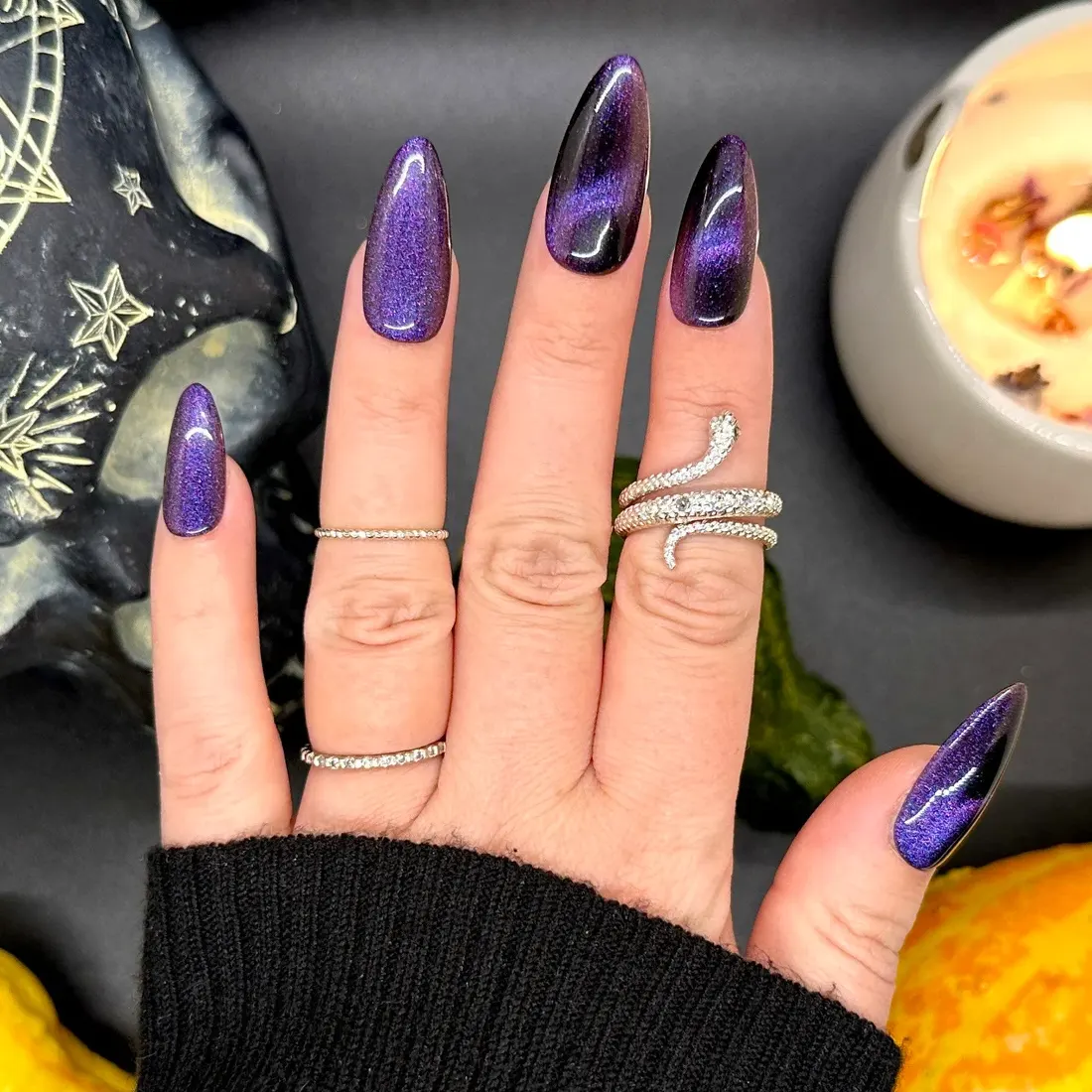 Closeup of hand with sparkly purple nail polish in a "cat eye" design | 9 Witchy Nail Designs You Can Buy as Press-Ons on Etsy | Slashed Beauty