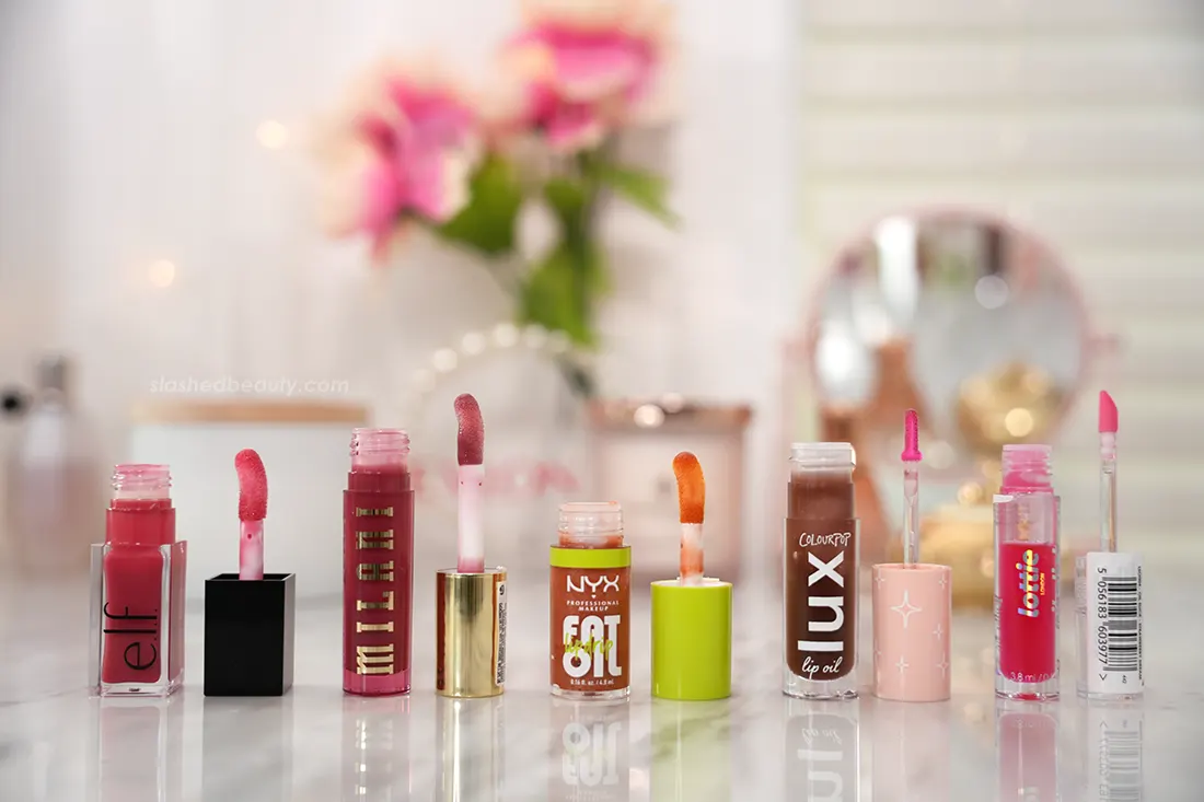 Five drugstore lip oils lined up side by side with their applicators. | The 5 Best Drugstore Lip Oils Tested & Compared | Slashed Beauty