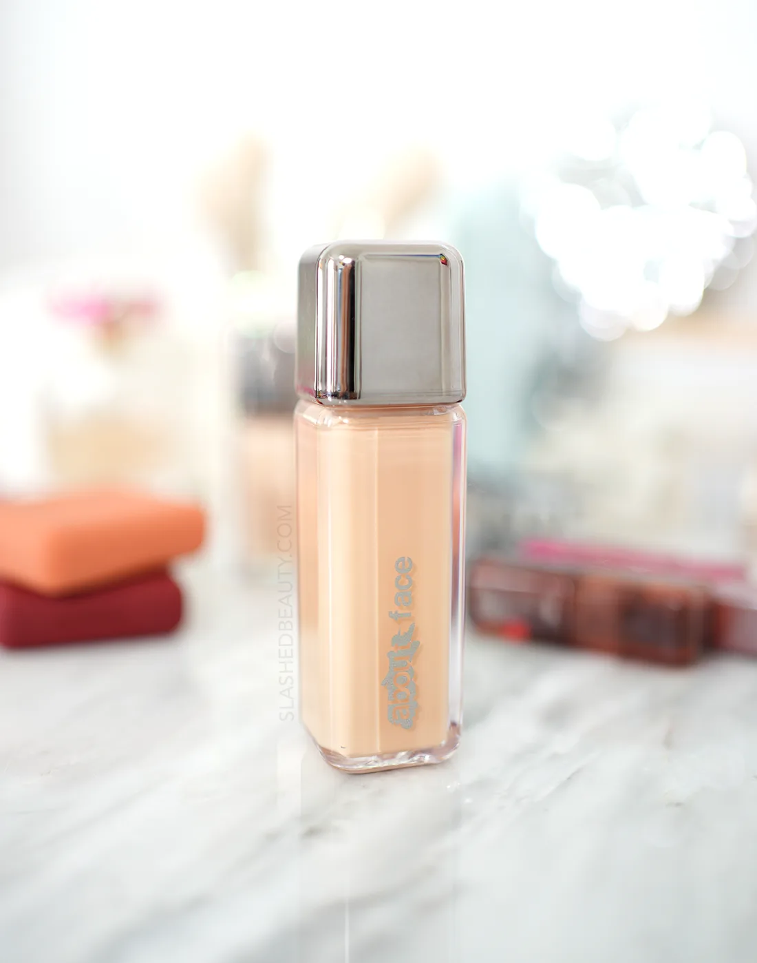 Closed bottle of about-face The Performer Skin Focused Foundation on a marble vanity among other beauty products. | about-face Foundation Review | Slashed Beauty